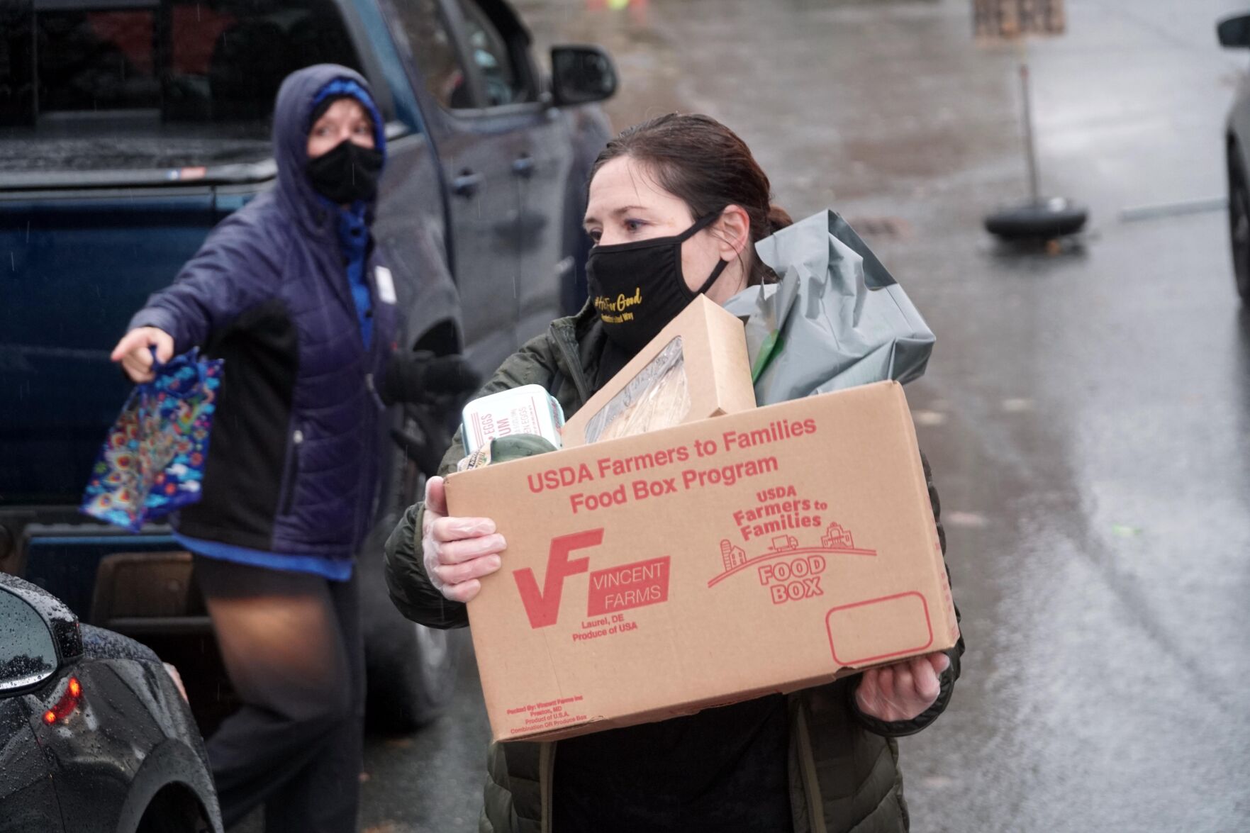 Volunteer loading box of food into cars outside